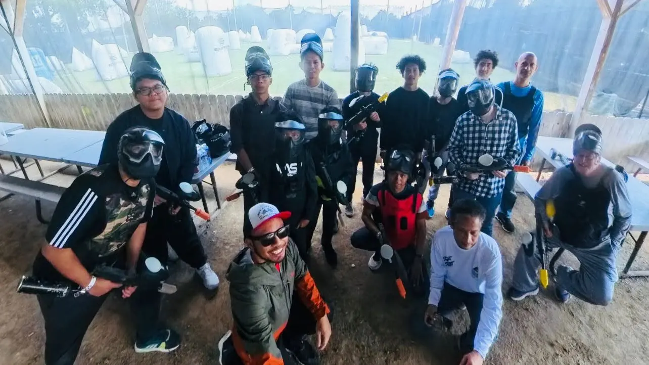 Bapak-bapak and teens in paintball gear posing together