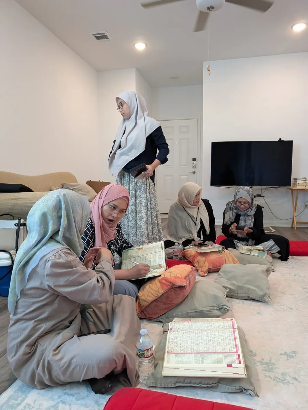 Sisters sitting on the floor reading Qur'an at home