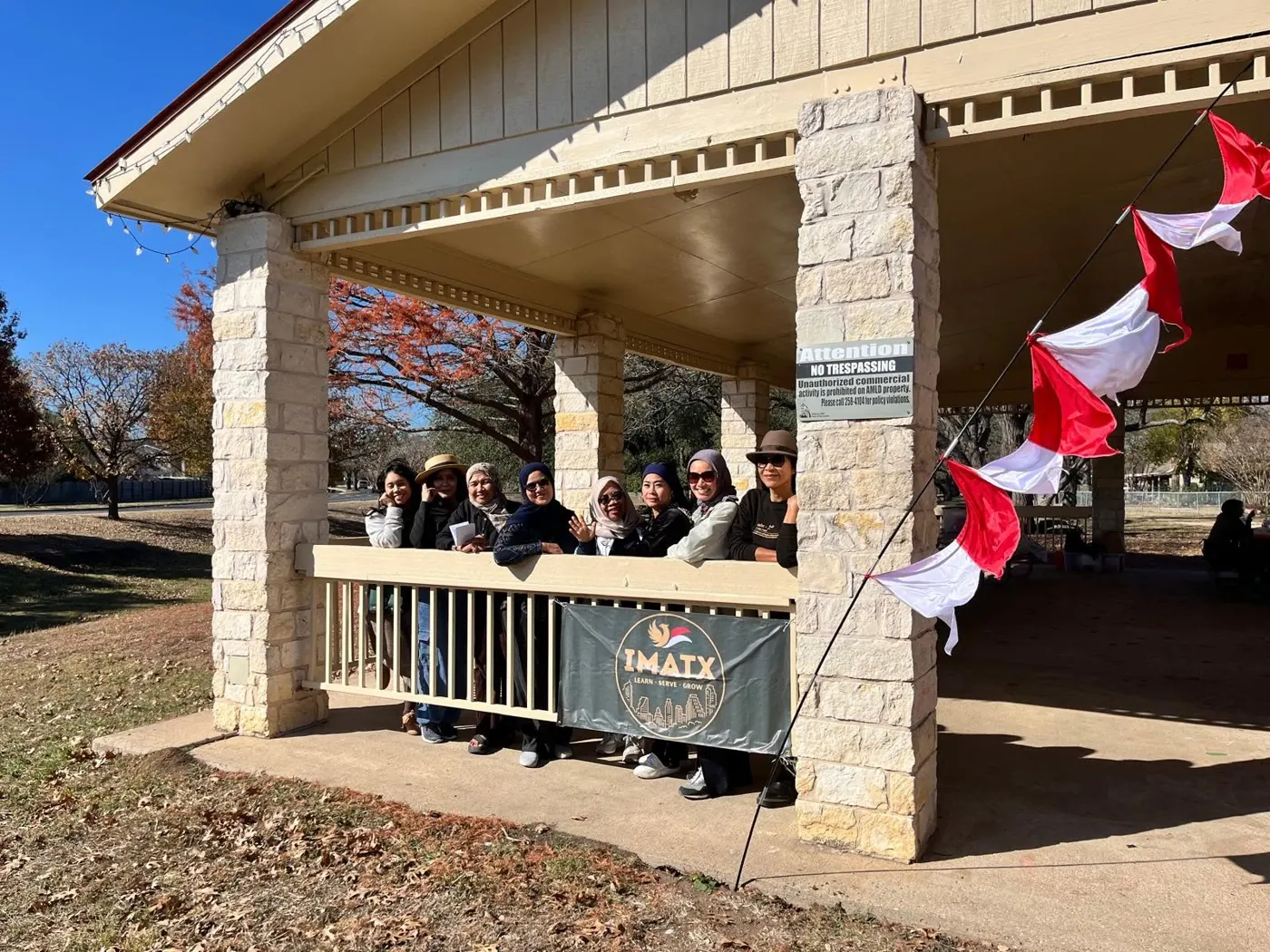 IMATX banner and red-white flags at a park pavilion
