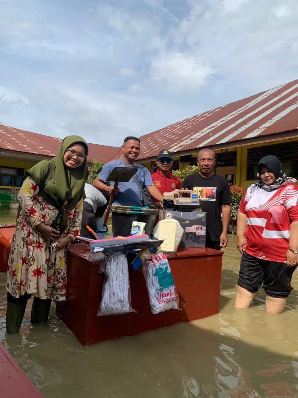 Volunteers at a school desk surrounded by flood water
