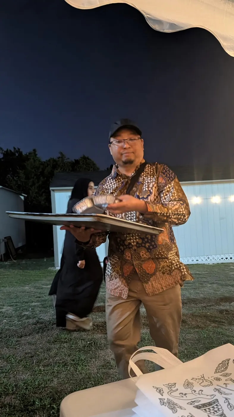 A volunteer carrying a tray of food at night